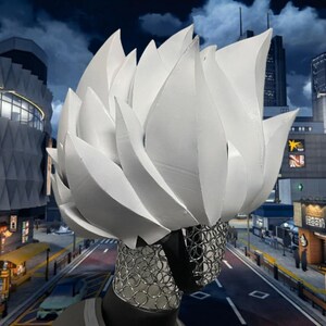 May include: A white, stylized headpiece resembling a burst of stylized flames or petals. The headpiece is paired with a silver mesh face covering. The background features a cityscape under a cloudy night sky.