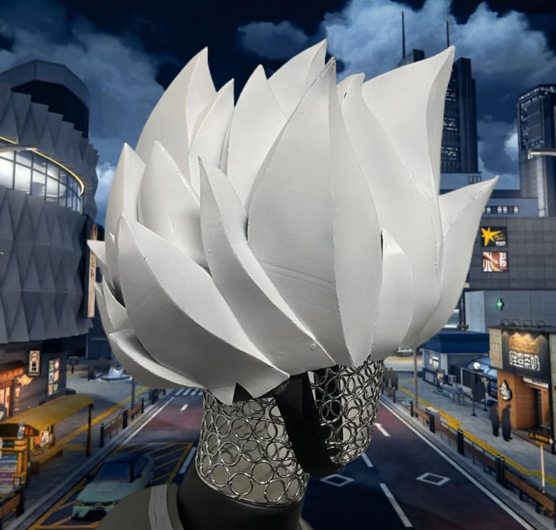 May include: A white, stylized headpiece resembling a burst of stylized flames or petals. The headpiece is paired with a silver mesh face covering. The background features a cityscape under a cloudy night sky.