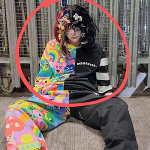 May include: A split-design outfit featuring a colorful, patterned top and pants on the left, and a black top and pants on the right. The top has the word "whatever." printed on it. The outfit is paired with black boots.