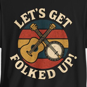 May include: Black t-shirt featuring a retro design with the text "LET'S GET FOLKED UP!" in a circular design. The design includes a guitar and banjo crossed over each other in the center.