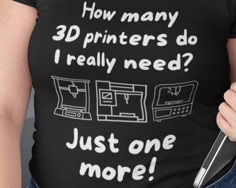 May include: Black t-shirt with the text "How many 3D printers do I really need? Just one more!" and three printer illustrations. The person is wearing blue jeans and glasses.