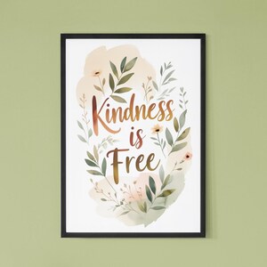 Può includere: Una stampa artistica da parete incorniciata con il testo "Kindness is Free" in un carattere corsivo con sfumatura marrone. Il testo è circondato da illustrazioni in stile acquerello di foglie verdi, steli sottili e piccoli fiori color pesca su sfondo bianco.