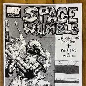 Puede incluir: Portada de cómic en blanco y negro titulada "SPACE WUMBLE" de Jim Hobbs. La portada presenta una ilustración detallada de una figura parecida a un robot sosteniendo un arma, con el texto "CLICK CLICK" y "WARNING" visibles. El logo de Riot! Comics está en la parte superior.