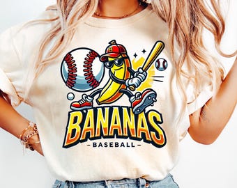 May include: Cream-colored t-shirt featuring a cartoon banana playing baseball. The banana wears sunglasses, a baseball cap, and red sneakers, holding a bat. The shirt has the words "BANANAS - BASEBALL-" in a bold, orange and yellow font.