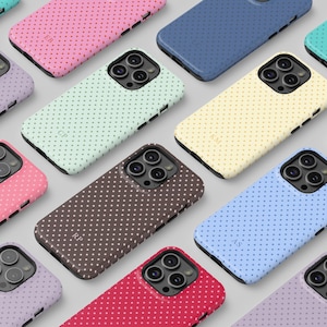 May include: A collection of colorful phone cases with a polka dot pattern. The cases are in various colors, including pink, blue, green, yellow, and brown. Each case has a different set of initials. The cases are designed to fit a smartphone.