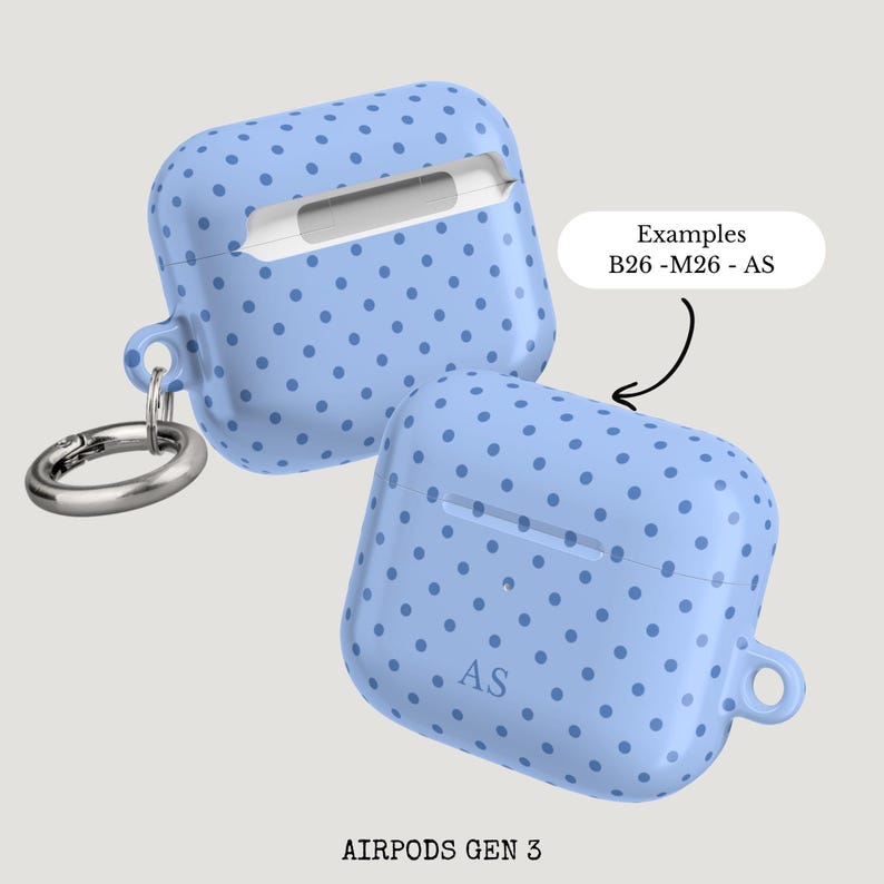 Puede incluir: Dos fundas celestes para AirPods Gen 3 con un dise&ntilde;o de lunares. Una funda tiene un mosquet&oacute;n plateado. El texto "Examples B26-M26-AS" est&aacute; en un &oacute;valo blanco. Las iniciales "AS" est&aacute;n en una funda.