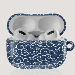 以下が含まれることがあります： 白い雲模様のネイビーブルーのAirPods Proケース。ケースは開いており、内部には白いイヤホンが見えます。ケースの側面には小さなハンドルが付いています。