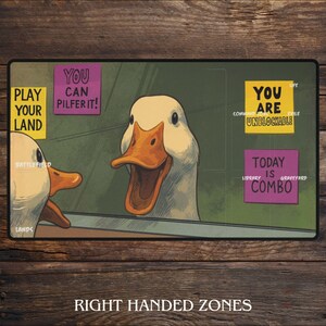 K&ouml;nnte beinhalten: Rechteckige Spielmatte mit einer Cartoon-Gans-Illustration. Das Design enth&auml;lt Text wie "Play Your Land", "You Can Pilfer It!" und "You Are Unblockable". Die Matte ist f&uuml;r Rechtsh&auml;nderzonen konzipiert.