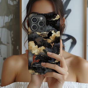 Peut inclure: Coque de téléphone noire avec un motif de dragon, représentant des dragons, des nuages et des étoiles. La coque porte la citation : « Une tragédie de dragon. Un cavalier est mort. »