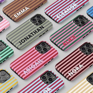 May include: A collection of personalized phone cases with vertical striped patterns in various colors, including pink, green, and brown. Each case features a name in a contrasting color.