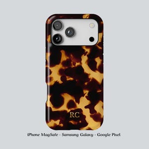 May include: A tortoiseshell-patterned phone case with a glossy finish. The case has a dark brown and amber color scheme, with the initials "RC" at the bottom. The case is designed for iPhone MagSafe, Samsung Galaxy, and Google Pixel phones.