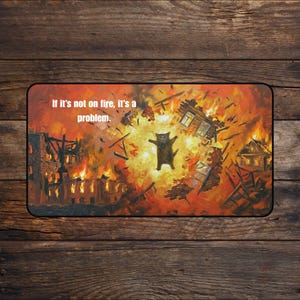 May include: A rectangular mousepad featuring a cat in the center of a fiery explosion. The image has a vibrant orange and red color scheme, with the text "If it's not on fire, it's a problem." printed at the top.