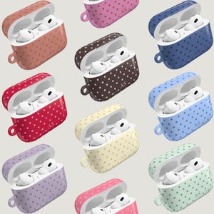 May include: A collection of polka-dot patterned AirPod cases in various colors, including red, brown, blue, and yellow. Each case is open, revealing white earbuds. The cases have a small loop for attachment.