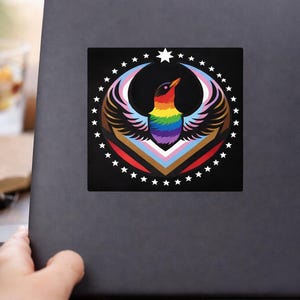 May include: A square sticker featuring a colorful bird design with rainbow feathers, a rainbow chest, and a black background. The bird is surrounded by a circle of white stars and a crescent shape with the colors of the transgender flag.