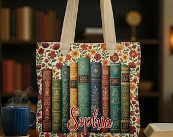 May include: A floral tote bag with cream-colored handles. The bag features a colorful floral pattern and a row of vintage book spines. The name "Sophia" is written in a cursive font across the books. A blue mug of coffee sits on a wooden table.