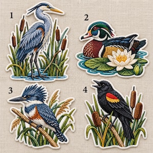 May include: Four embroidered patches featuring birds: a blue heron in reeds, a wood duck with a white water lily, a belted kingfisher on a branch, and a red-winged blackbird among cattails. Each patch is numbered one through four.