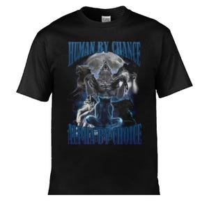 May include: Black t-shirt with a fantasy graphic of a werewolf howling at the moon, with wolves around it. The text "HUMAN BY CHANCE" and "ALPHA BY CHOICE" are in blue. A dark, gothic design.
