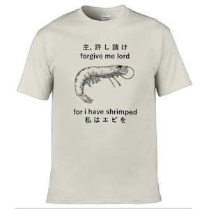 May include: Cream-coloured t-shirt featuring a shrimp graphic and text in English and Japanese. The text says "forgive me lord, for I have shrimped". A humorous design, ideal for casual wear.