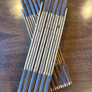 May include: A set of two vintage wooden folding rulers with blue and brown painted markings. The rulers are folded and stacked on top of each other.