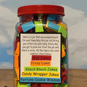 May include: A clear glass jar with a red lid, filled with colourful paper notes. The jar contains notes with topics such as "Dad Jokes" and "Fortune Cookie Wisdom". A label on the jar provides instructions.