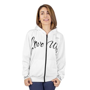 May include: White zip-up hoodie featuring the words "Love Wins" in black script. The hoodie has a black zip and the word "CORVILLE" on the upper right chest. The sleeves have the word "Love" on them.