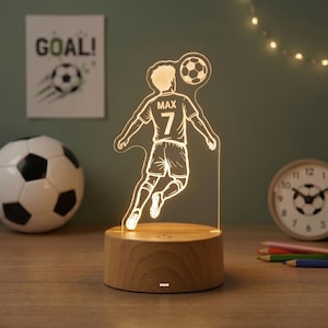 May include: A football-themed night light with a player silhouette, the name "Max" and the number "7" on the jersey. The light sits on a wooden base. A football and a "GOAL!" poster are in the background.