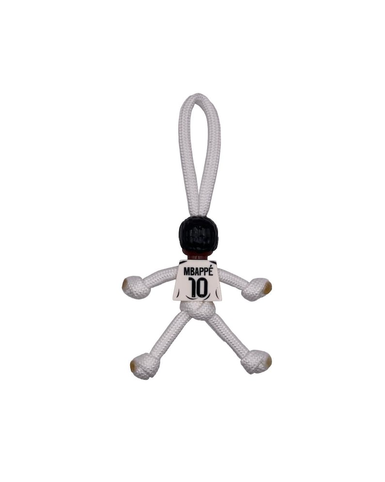 Może przedstawiać: Biały ceramiczny kubek z czarnym uchwytem i napisem "But First, Coffee" czarną, odręczną czcionką. Kubek stoi na białej powierzchni.