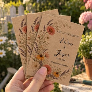 Może przedstawiać: Trzy prostokątne torebki na nasiona z papieru kraft z kwiatową ilustracją lawendy i polnych kwiatów. Tekst brzmi LET LOVE GROW, Wren & Jasper, 12.12.2026 oraz WILDFLOWER SEEDS. Torebki są ułożone w wachlarz na tle ogrodu.