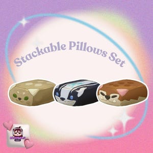 Op de afbeelding: Een set van drie stapelbare kussens met dierengezichten. De kussens zijn rechthoekig met afgeronde randen. Eén is beige met een kattengezicht, één is zwart en wit met een stinkdiergezicht en één is bruin met een berengezicht. De tekst "Stackable Pillows Set" staat erboven.