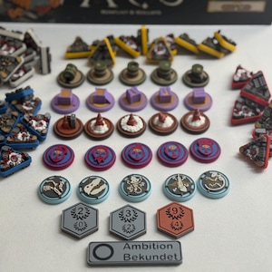 Könnte beinhalten: Eine Sammlung von Brettspielkomponenten, darunter verschiedene Spielsteine, dreieckige Teile und sechseckige Kacheln. Die Spielsteine weisen unterschiedliche Designs und Farben wie Rot, Blau und Gelb auf. Die Spielteile sind auf einer weißen Oberfläche angeordnet.
