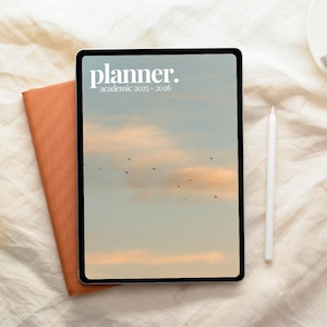 Puede incluir: Un planificador digital con el texto "planner. academic 2025-2026" en la pantalla. La pantalla muestra un cielo con nubes y pájaros. Un cuaderno naranja y un lápiz blanco están junto al planificador.