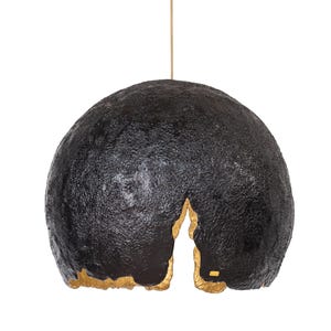 Puede incluir: Lámpara colgante negra con superficie texturizada y un acento dorado en la parte inferior. La lámpara cuelga de un fino cable de color claro sobre un fondo blanco. La lámpara tiene una forma orgánica única.