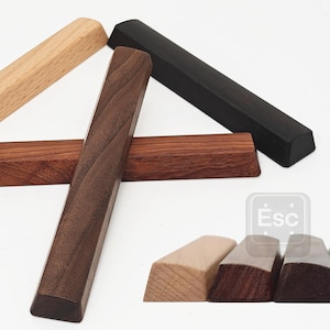Puede incluir: Un surtido de teclas de teclado de madera en varios colores y acabados. Las teclas están hechas de madera e incluyen opciones marrón claro, marrón oscuro y negro. Las teclas son rectangulares con bordes angulados.