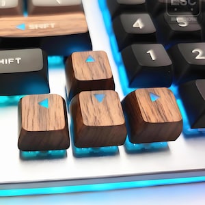 May include: Close-up of a mechanical keyboard with custom wooden keycaps. The keycaps have a wood grain texture and feature a blue arrow symbol. The keyboard has a white base with blue LED lighting.
