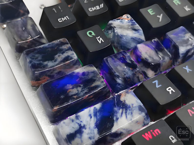 May include: Close-up of a computer keyboard with custom keycaps. The keycaps are made of a translucent material with a blue and white marbled pattern. Some keys have Cyrillic characters.