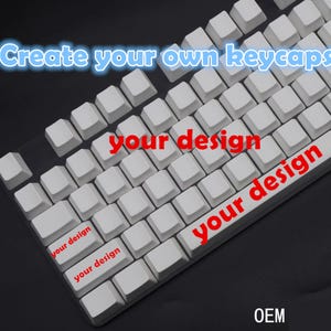 Puede incluir: Primer plano de un teclado mecánico blanco con teclas en blanco. El texto "Create your own keycaps" está en azul y "your design" en rojo. La palabra "OEM" está en la esquina inferior derecha.