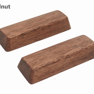 Op de afbeelding: Twee rechthoekige, massieve stukken walnotenhout met schuine randen. De houtnerf is zichtbaar en de stukken hebben een warme bruine kleur. Het woord "Walnut" staat in de linkerbovenhoek.