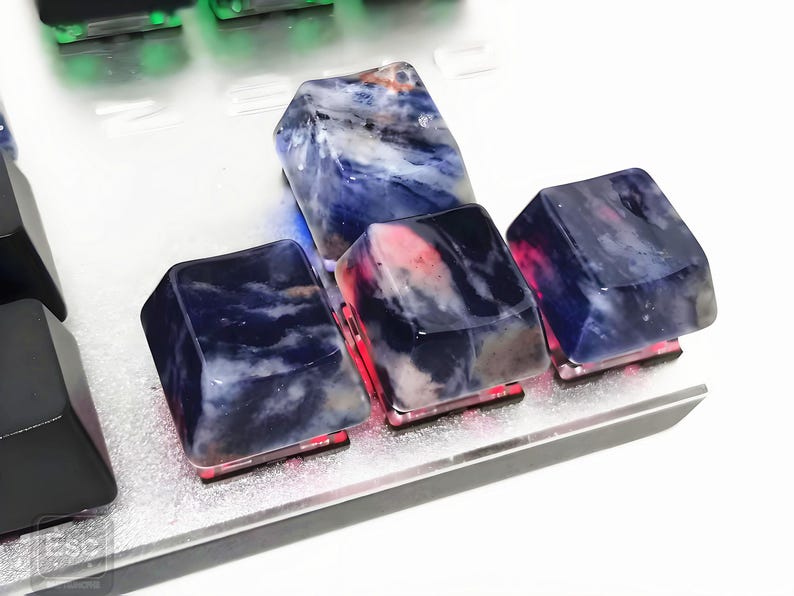 May include: Close-up of custom keyboard keycaps. The keycaps are made of a translucent material with a blue and white marbled pattern. The keycaps are lit from below with red and blue lights, creating a unique aesthetic.