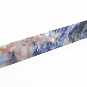 May include: A rectangular crystal wand with a polished finish. The wand features a blend of blue, white, and peach hues, creating a marbled effect. The crystal is a solid, elongated shape, perfect for display or use.