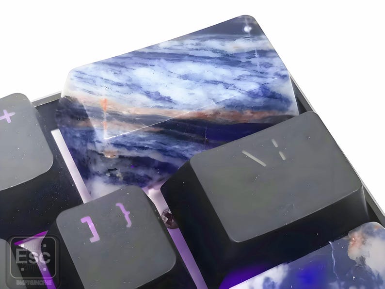 May include: Close-up of a mechanical keyboard with custom keycaps. The keycaps feature a blue and white marbled design, with some keys in black. The keyboard has a metallic frame and purple backlighting.