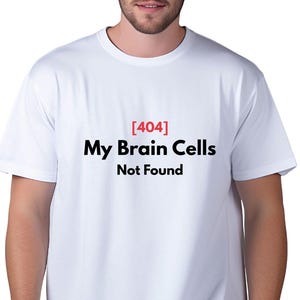 May include: White t-shirt with the text "[404] My Brain Cells Not Found" in black and red. The shirt is a crew neck style and is being worn.