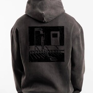 Könnte beinhalten: Dunkelgrauer Kapuzenpullover mit schwarzer Grafik auf dem Rücken. Die Grafik zeigt eine Person auf einer Straße mit dem Text "EMPTY ST" auf einem Straßenschild. Der Hoodie hat eine Kapuze und lange Ärmel.