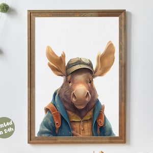 Könnte beinhalten: Ein gerahmter Aquarelldruck eines Elchs mit Mütze, blauer Jacke und kariertem Hemd. Der Elch hat ein großes Geweih und einen freundlichen Ausdruck. Der Druck ist in einem Holzrahmen und hat den Text "printed in 24h".