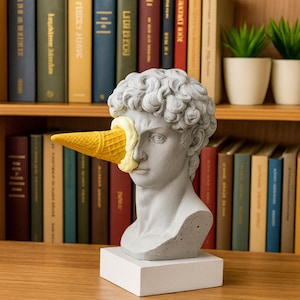 Peut inclure: Buste gris d'une figure classique avec un cornet de glace à la place d'un œil. Le cornet est jaune et rempli d'une substance crémeuse jaune clair. Le buste est sur une base carrée blanche.