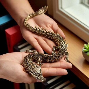 May include: A detailed, golden dragon figurine with a textured surface. The dragon is posed in a curved shape, with its head and tail raised. The dragon's scales and features are intricately designed, showcasing a mythical creature.