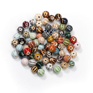 May include: A selection of ceramic beads in assorted colours and patterns. The beads are spherical with a central hole, and feature stripes, dots, and floral designs. Colours include brown, blue, green, and pink.