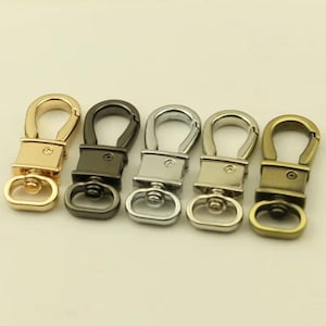 May include: Five metal swivel clasps in various finishes: gold, black, silver, and antique brass. Each clasp features a swivel ring and a spring-loaded hook for easy attachment to bags, keychains, or other accessories.