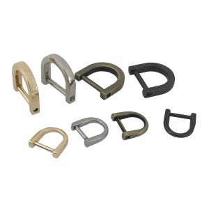 Könnte beinhalten: Verschiedene D-Ring-Schnallen in verschiedenen Metallausführungen, darunter Gold, Silber, Bronze und Schwarz. Diese Metallbeschläge sind für Taschen, Gürtel und andere Bastelprojekte geeignet. Die Schnallen werden vor weißem Hintergrund gezeigt.