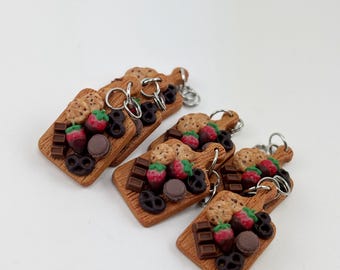 May include: Six miniature wooden cutting boards with a variety of chocolate, cookies, and strawberries. Each board has a silver key ring attached.