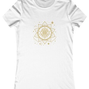 May include: White t-shirt featuring a gold geometric design. The design is a detailed mandala with a central pattern and surrounding stars and crescent moons. The shirt has a crew neck and short sleeves.